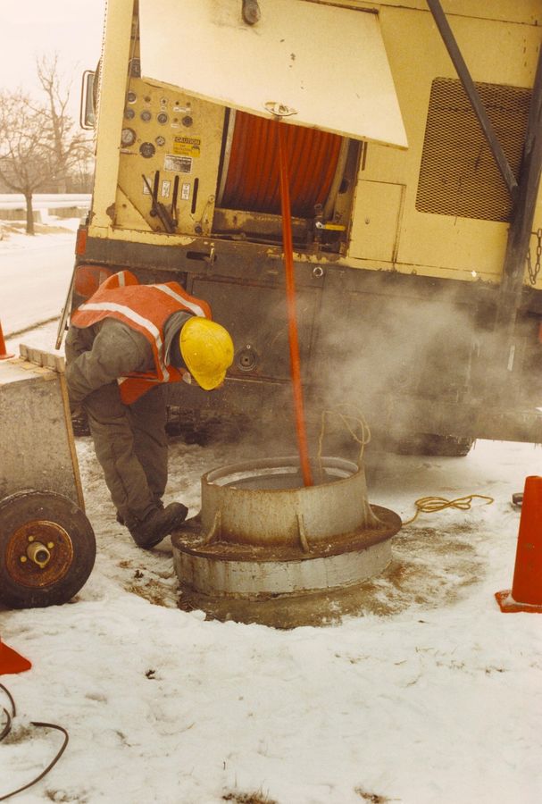 Technician jetting a line through an open manhole